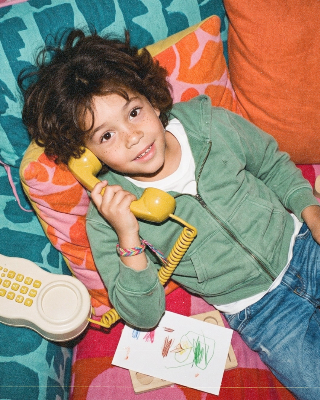 Enfant avec un téléphone combiné jaune sur un lit