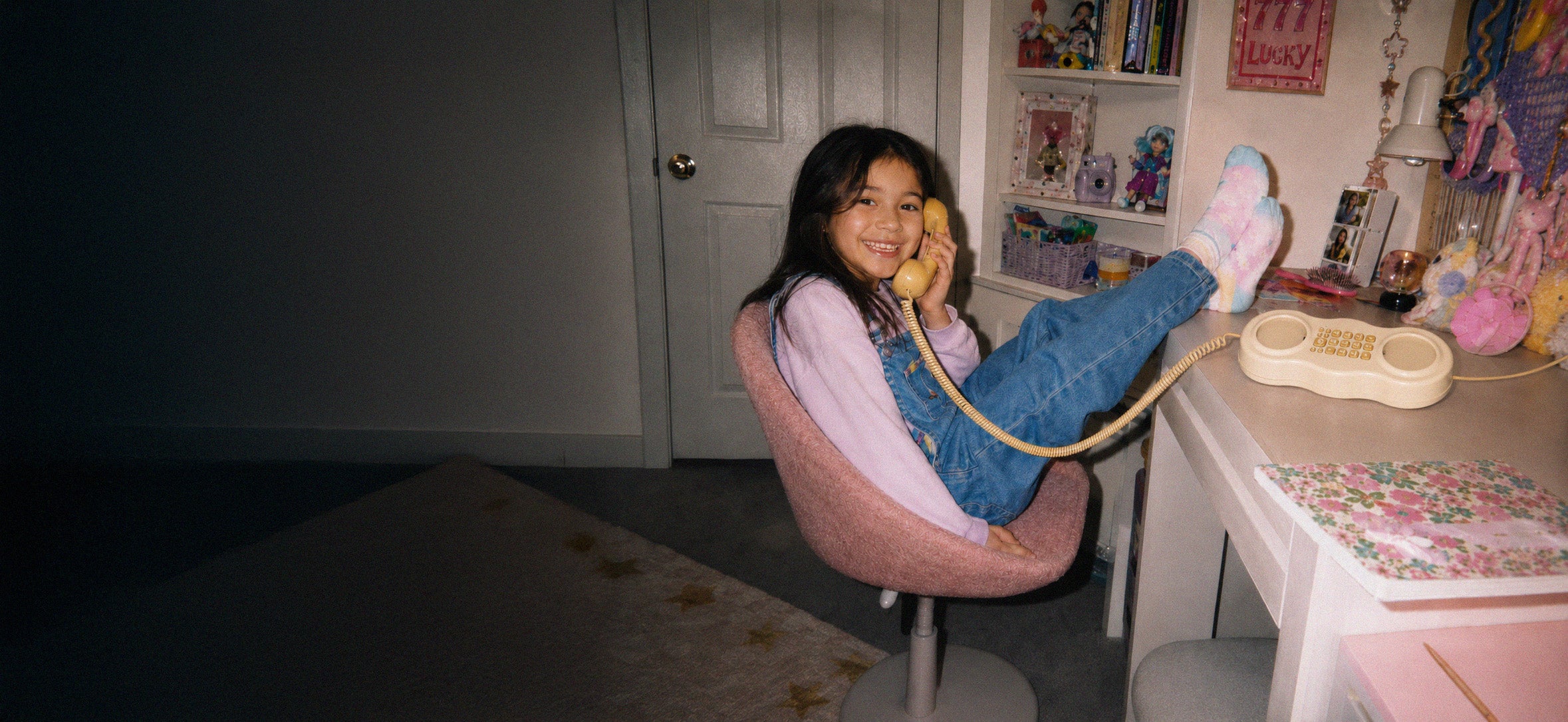 Petite fille avec un téléphone combiné jaune sur un bureau 