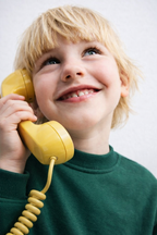 Petit garçon avec un téléphone Combiné jaune